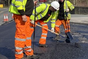 Tar.co.uk is for sale. Workmen raking tarmac on a road